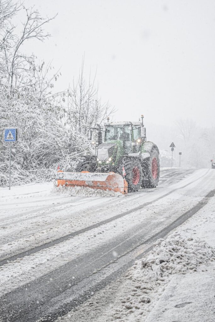 A snowplow clearing heavy winter snow from a road in Como, Italy, ensuring safe transportation.