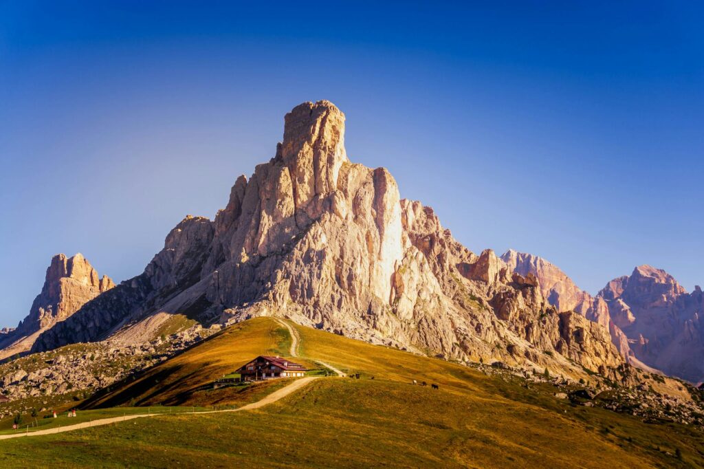 Breathtaking view of Dolomite peaks at sunrise with a quaint lodge nestled amidst the rocky landscape.